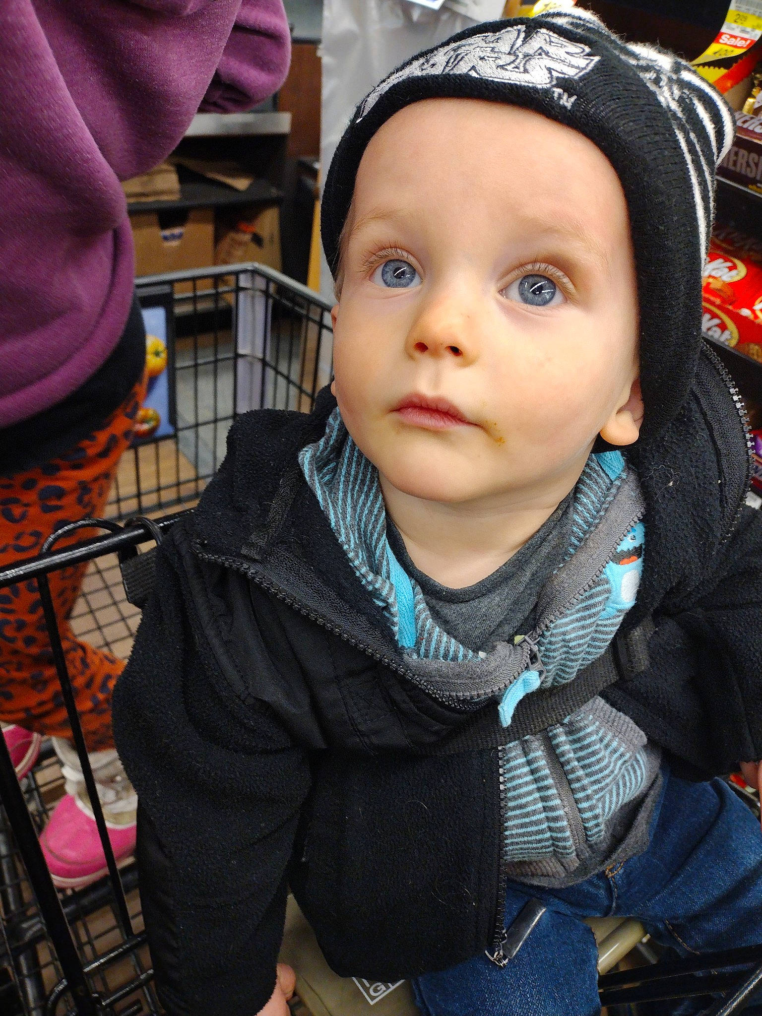 Mathias is registered to the contest to win money with this photo: baby, cap, cheek, child, city, cool, electric_blue, eyelash, fashion_accessory, fun, happy, outerwear, person, public_space, purple, sitting, snapshot, surprise, toddler, tradition