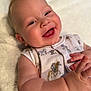 adorable, baby, blanket, cartoon_print, child, closeup, cute, expression, face, hands, happy, indoors, infant, lying_down, mohawk, onesie, playful, skin, smiling, soft_texture