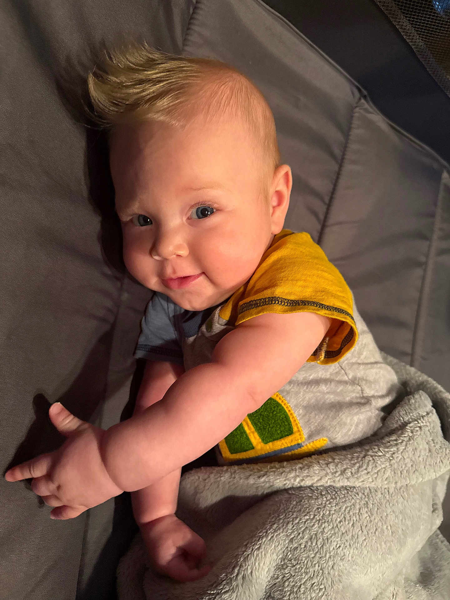 Kohen joined the competition — help win amazing prizes! baby, child, infant, smile, face, arm, blanket, shirt, blue_eyes, mohawk_hairstyle, lying_down, cozy, soft, cute, indoors, person, skin, happy, toddler, portrait