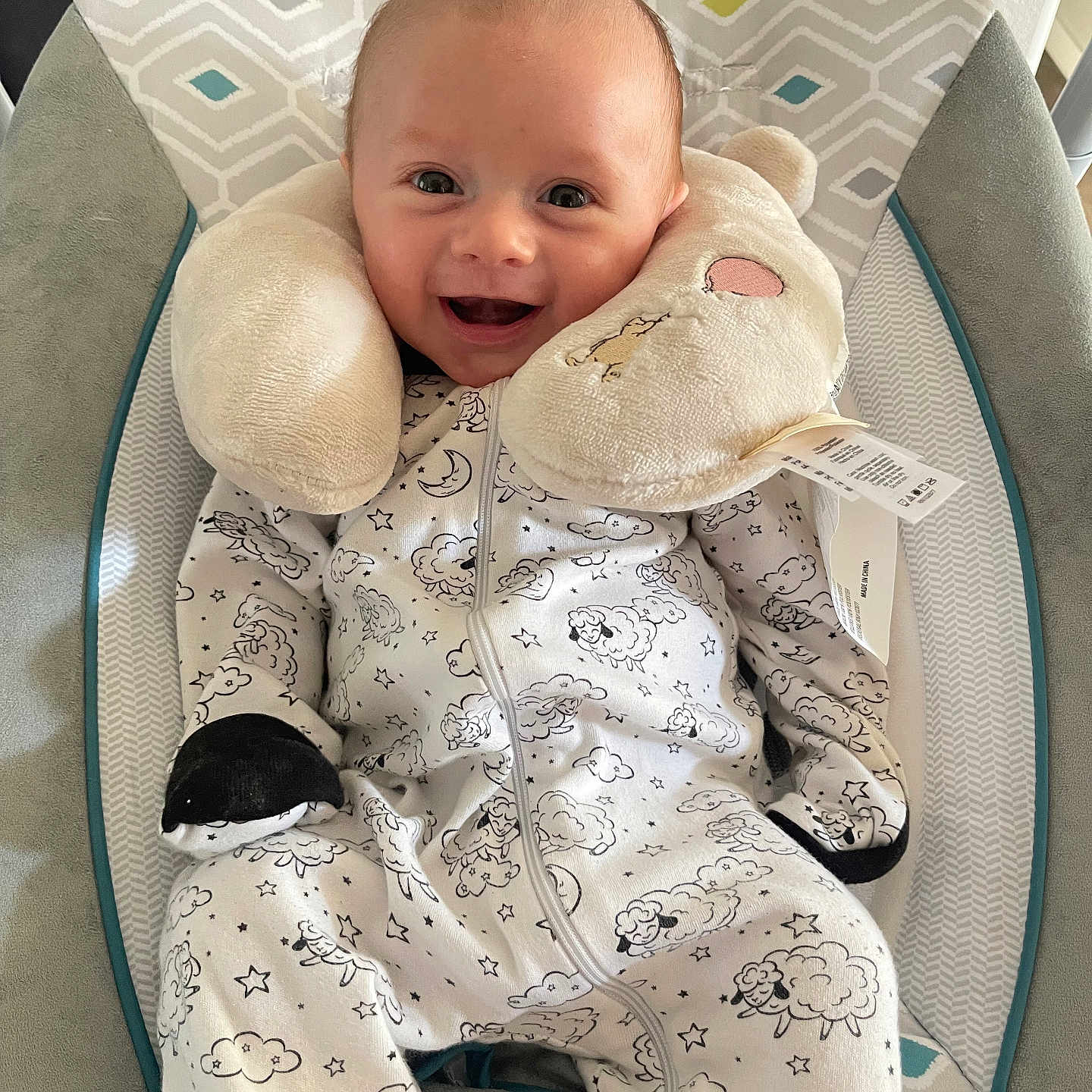 Micah is registered to the contest to win money with this photo: baby, baby_chair, child, clothing, comfort, cushion, cute, face, happy, indoors, infant, onesie, pattern, plush, relaxation, seated, sleeping_pillow, small_person, smile, soft_toy