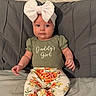 baby, child, girl, headband, bow, green_shirt, floral_pants, sitting, bed, gray_pillows, cute, infant, clothing, portrait, indoor, soft_lighting, expression, hands, feet, comfortable