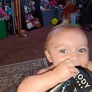 Andrea joined the competition — help win amazing prizes! baby, child, infant, portrait, close_up, face, eyes, blue_eyes, blond_hair, smiling, curious, hand, biting, book, reading, toys, playroom, carpet, indoor, home