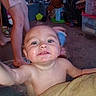 Andrea is registered to the contest to win money with this photo: baby, child, infant, smiling, happy, portrait, face, eyes, drool, bare_chested, sitting, indoor, playroom, toys, dolls, storage_bins, carpet, adult_legs, closeup, family_home