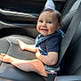 Raiden is registered to the contest to win money with this photo: baby, child, birthday_hat, car_seat, seatbelt, smile, barefoot, sunlight, happy, infant, clothing, denim_overalls, black_shirt, car_interior, leather_seat, window, portrait, cute, sitting, face