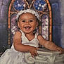 toddler, child, smiling, white_dress, headband, flower_crown, column, portrait, indoor, happy, cute, baby, face, hands, standing, background, decorative, stained_glass, window, photography