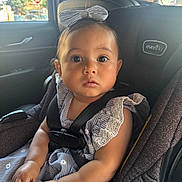 Raiden is registered to the contest to win money with this photo: baby, child, car_seat, car_interior, seatbelt, bow, dress, lace, striped, person, infant, sitting, hands, face, eyes, window, door, adult, vehicle, safety