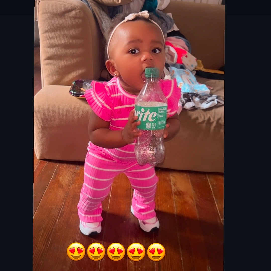 Nevaeh joined the competition — help win amazing prizes! architecture, baby, bottle, building, clothing, couch, face, footwear, furniture, hat, head, indoors, interiordesign, livingroom, person, photography, portrait, room, shoe, sitting