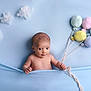 baby, infant, blue_background, plush_balloons, cotton_clouds, soft_texture, child, cute, portrait, smiling, holding, blanket, studio_photo, happy, young_child, playful, indoors, decor, fabric, toy
