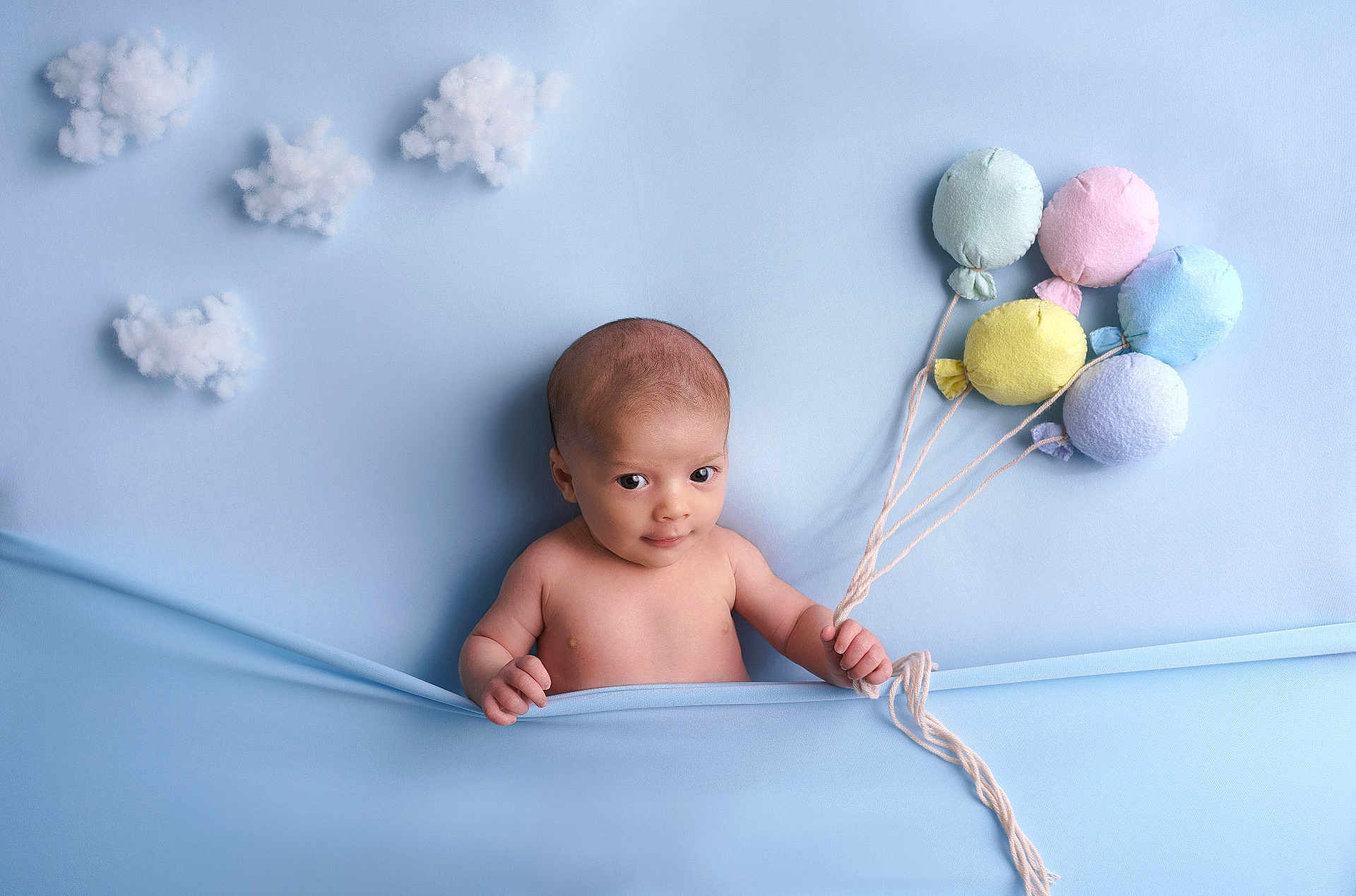 Salomé a rejoint le concours — aidez-le/la à gagner de superbes lots ! baby, infant, blue_background, plush_balloons, cotton_clouds, soft_texture, child, cute, portrait, smiling, holding, blanket, studio_photo, happy, young_child, playful, indoors, decor, fabric, toy
