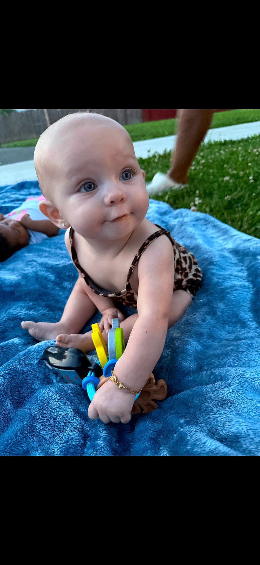 Kalayah joined the competition — help win amazing prizes! baby, child, outdoor, grass, blanket, toy, blue_blanket, sitting, curious, person, grass_lawn, playing, infant, jewelry, bracelet, earrings, summer, daylight, cute, young_child