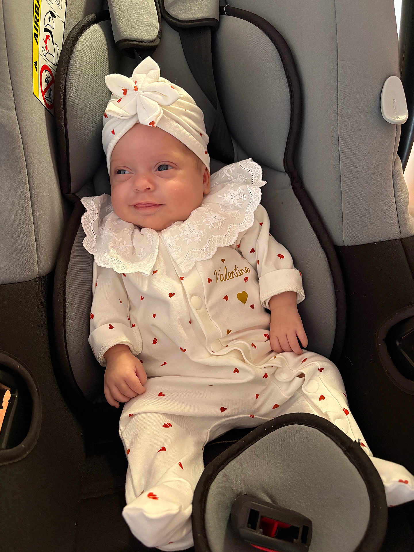 Valentine a rejoint le concours — aidez-le/la à gagner de superbes lots ! baby, infant, car_seat, headband, flower, white_outfit, hearts_pattern, smile, cute, child, seatbelt, clothing, soft_lighting, indoor, portrait, young_child, baby_girl, cozy, comfortable, closeup