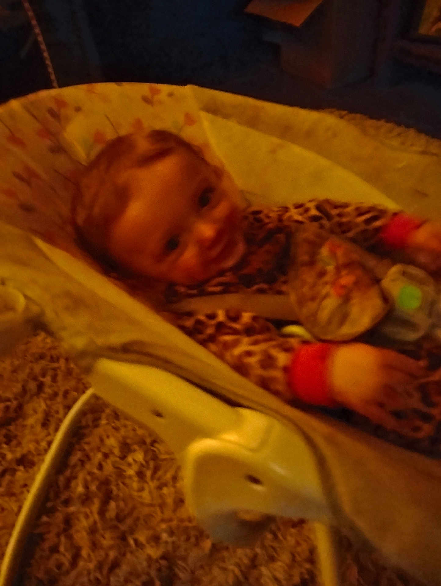 Lillian is registered to the contest to win money with this photo: baby, infant, baby_rocker, leopard_print, carpet, smile, child, indoor, seat, toy, clothing, person, blur, low_light, happy, young_child, baby_toys, seat_belt, face, furniture