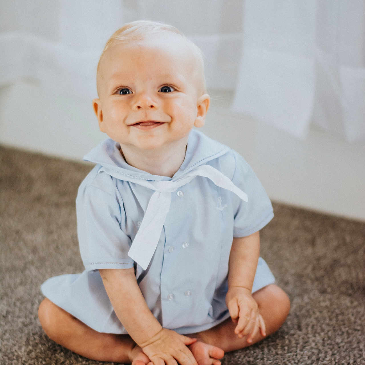 Ryatt is registered to the contest to win money with this photo: baby, blond_hair, blue_clothing, carpet, child, curtains, cute, face, feet, floor, hands, happy, indoor, infant, person, portrait, sailor_outfit, sitting, smiling, young_child