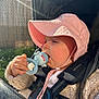 baby, infant, stroller, sun_hat, pacifier, hand, harness, knit_sweater, outdoors, sunlight, lens_flare, close_up, portrait, pink_hat, baby_toy, seat, safety_strap, chewing, cute, daylight