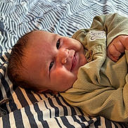 Enzo-Hency joined the competition — help win amazing prizes! baby, bed, child, closeup, clothing, cozy, cute, expression, face, happy, indoor, infant, lying_down, natural_light, person, portrait, skin, smile, striped_bedspread, young