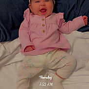 Christina is registered to the contest to win money with this photo: baby, infant, child, smiling, pink_outfit, headband, bow, pajamas, bed, bedding, pillow, blanket, indoors, portrait, sitting, happy, face, morning, timestamp, photograph