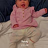 baby, infant, child, smiling, pink_outfit, headband, bow, pajamas, bed, bedding, pillow, blanket, indoors, portrait, sitting, happy, face, morning, timestamp, photograph