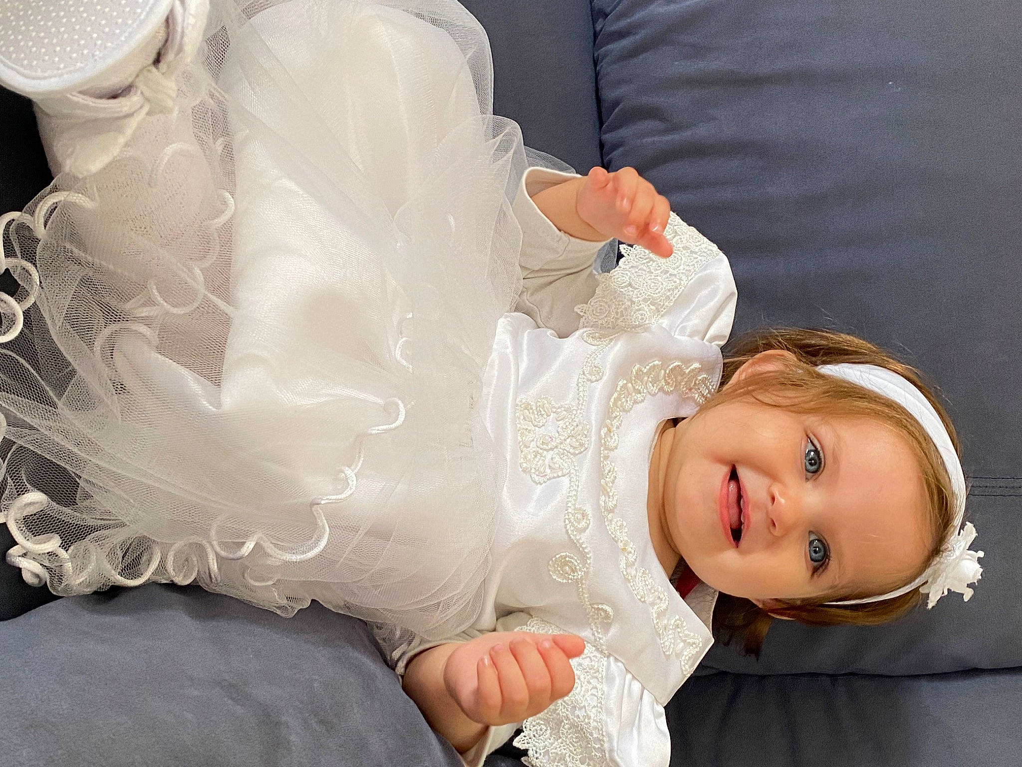 Myléna participe au concours pour gagner de l'argent avec cette photo : baby, baby_toddler_clothing, blond, bridal_accessory, child, dress, embellishment, event, fashion_accessory, flash_photography, fun, gesture, happy, head, headpiece, jewellery, joy, person, sitting, sleeve
