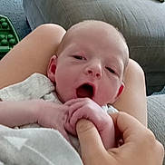 Leo joined the competition — help win amazing prizes! baby, infant, hand, blanket, person, living_room, couch, carpet, toy, exercise_ball, furniture, comfort, sleepy, holding, skin, closeup, indoor, relaxing, family, cozy