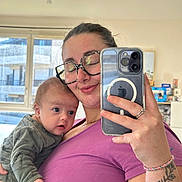Raphaël a rejoint le concours — aidez-le/la à gagner de superbes lots ! woman, baby, infant, mirror_selfie, smartphone, glasses, purple_shirt, tattoo, ring, bracelet, window, indoor, family, holding, portrait, reflection, newborn, cozy, home, smile