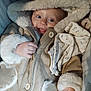 baby, child, smile, coat, hood, fur_trim, hand, clothing, fabric, blanket, cushion, comfort, cute, infant, warm, portrait, face, eyes, indoors, soft
