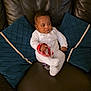 baby, infant, couch, leather, blue_cushions, white_onesie, wristband, indoor, child, sitting, furniture, relaxed, looking_away, hand, footwear, person, home, comfort, portrait, cute
