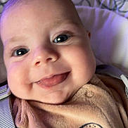 Raphaël a rejoint le concours — aidez-le/la à gagner de superbes lots ! baby, face, tongue, smile, close_up, infant, child, cute, happy, clothing, bear_design, strap, eyes, cheeks, soft_background, indoors, person, young_child, cozy, portrait