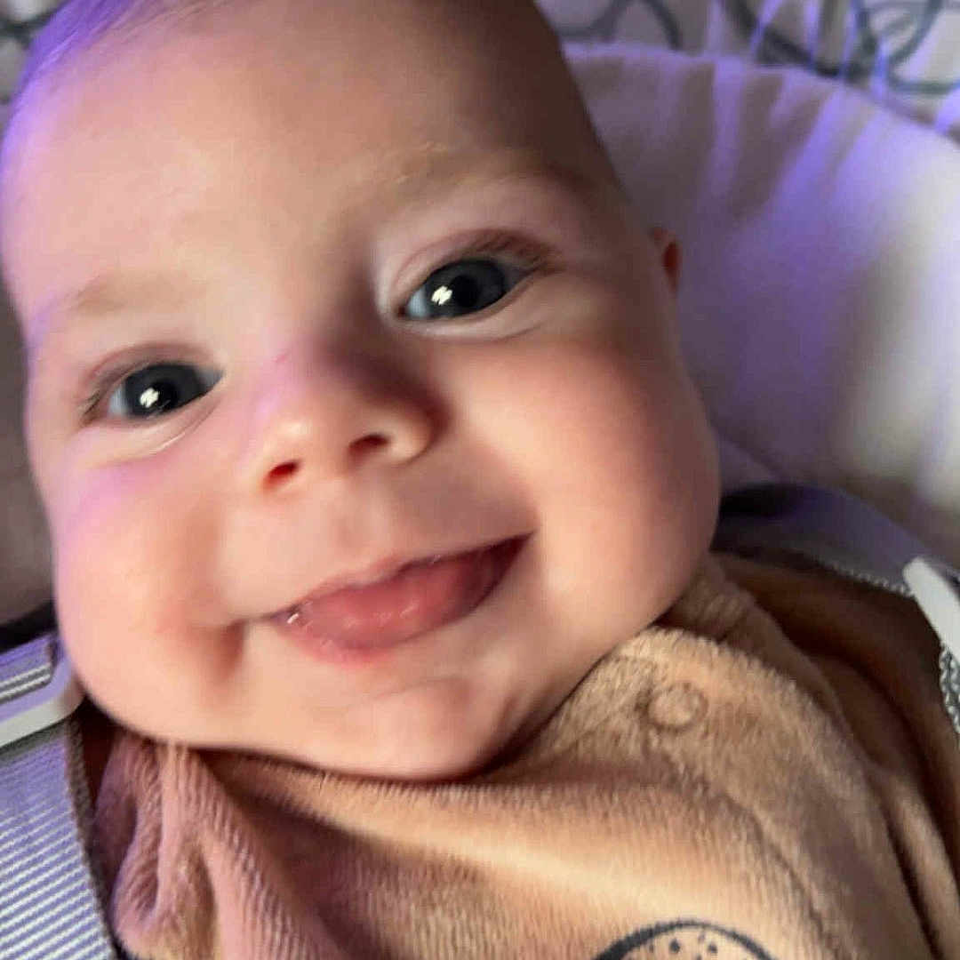 Raphaël a rejoint le concours — aidez-le/la à gagner de superbes lots ! baby, bear_design, cheeks, child, close_up, clothing, cozy, cute, eyes, face, happy, indoors, infant, person, portrait, smile, soft_background, strap, tongue, young_child