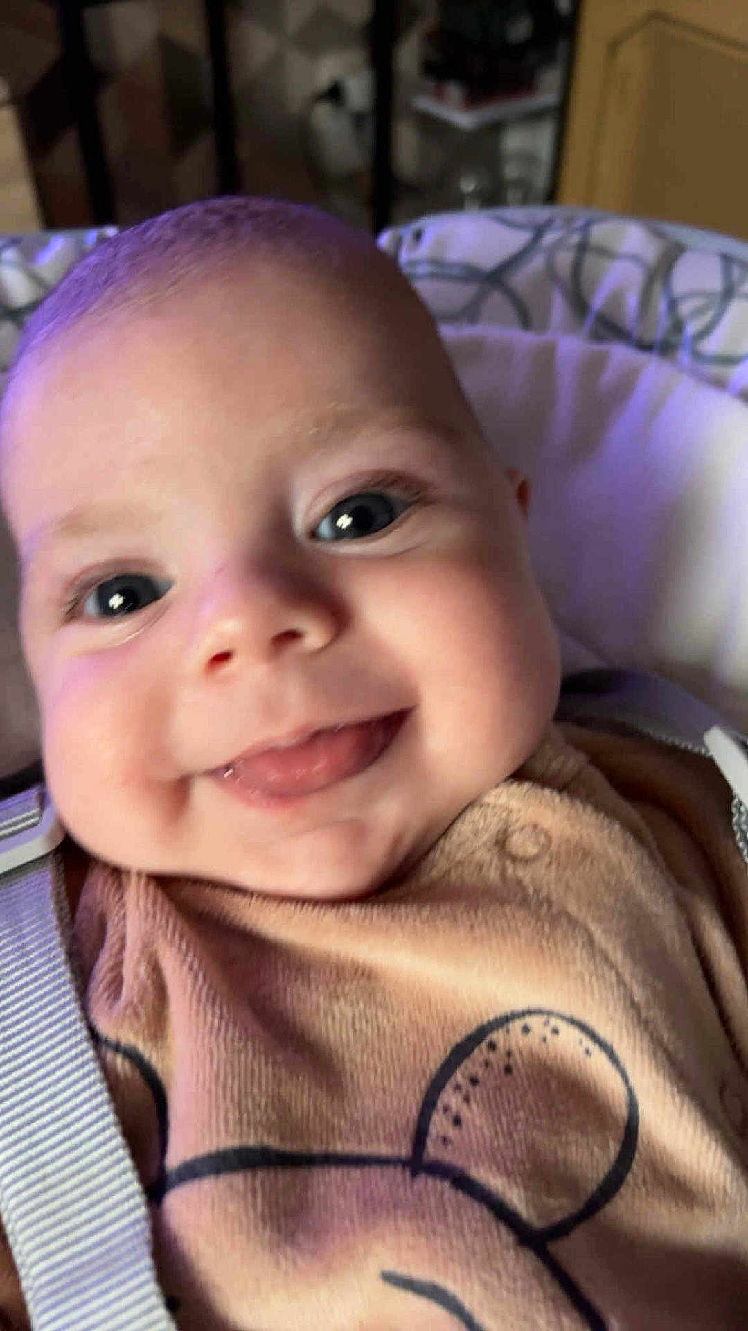 Raphaël a rejoint le concours — aidez-le/la à gagner de superbes lots ! baby, face, tongue, smile, close_up, infant, child, cute, happy, clothing, bear_design, strap, eyes, cheeks, soft_background, indoors, person, young_child, cozy, portrait