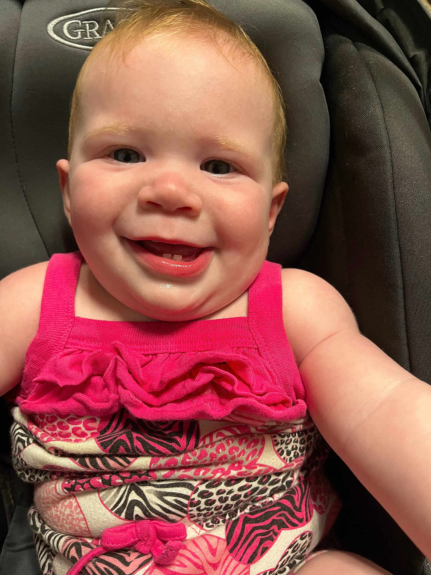 Naomi is registered to the contest to win money with this photo: baby, child, smiling, face, pink_clothing, car_seat, infant, happy, cute, portrait, skin, person, cheerful, young, seat, fabric, pattern, closeup, head, expression
