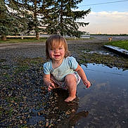 Oaklynn joined the competition — help win amazing prizes! toddler, child, muddy, puddle, outdoor, playing, happy, smiling, dirt, grass, trees, sky, dog, rocks, nature, barefoot, squatting, casual_clothing, sunset, fun