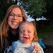 Oaklynn is registered to the contest to win money with this photo: backyard, casual, child, daylight, face, family, glasses, grass, happy, hoodie, nature, outdoor, pacifier, pavement, person, smile, sunlight, toddler, trees, woman