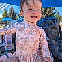 toddler, child, smiling, outdoor, sunny, sun_protection, sunscreen, floral_clothing, pink, table, backpack, nature, trees, blue_sky, happy, portrait, baby, playful, summer, canopy