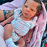 arm, baby, car_interior, chevrolet_logo, child, cozy, cute, floral_outfit, holding, infant, newborn, person, pink_blanket, portrait, pout, resting, socks, soft_texture, tattoo, wide_eyes