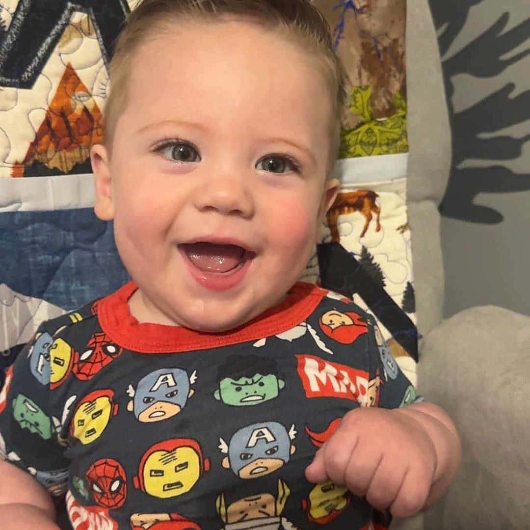 Logan is registered to the contest to win money with this photo: baby, babylaughing, bodypart, clothing, cushion, face, furniture, happy, head, homedecor, laughing, mouth, person, photography, plant, portrait, quilt, smile, t_shirt, teeth