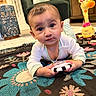 baby, carpet, child, colorful, curious, cute, floor, furniture, home, indoor, infant, living_room, pattern, person, pillow, play, plush_giraffe, rug, toy, young_child