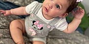 Sofia is registered to the contest to win money with this photo: baby, child, girl, sitting, pink_bows, minnie_mouse, outfit, sparkly_shoes, bedspread, patterned, curious, indoor, cute, infant, portrait, clothing, person, young_child, hair_accessories, closeup