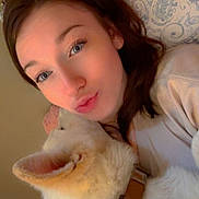 Kayda Jade is registered to the contest to win money with this photo: woman, dog, selfie, pillow, collar, snuggling, indoor, bedroom, closeup, face, pet, cute, cozy, fur, young_adult, casual_clothing, affection, resting, light_skin, brown_hair