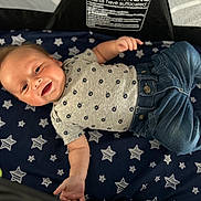 Carson joined the competition — help win amazing prizes! baby, smiling, infant, child, clothing, jeans, shirt, blanket, stars, happy, lying_down, cute, young_child, indoor, portrait, person, infant_clothing, casual, socks, baby_toys