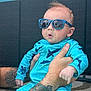 baby, child, sunglasses, tattoo, swimsuit, blue_clothing, outdoor, person, arm, hand, face, expression, poolside, concrete, summer, sunny, reflection, cute, infant, holding