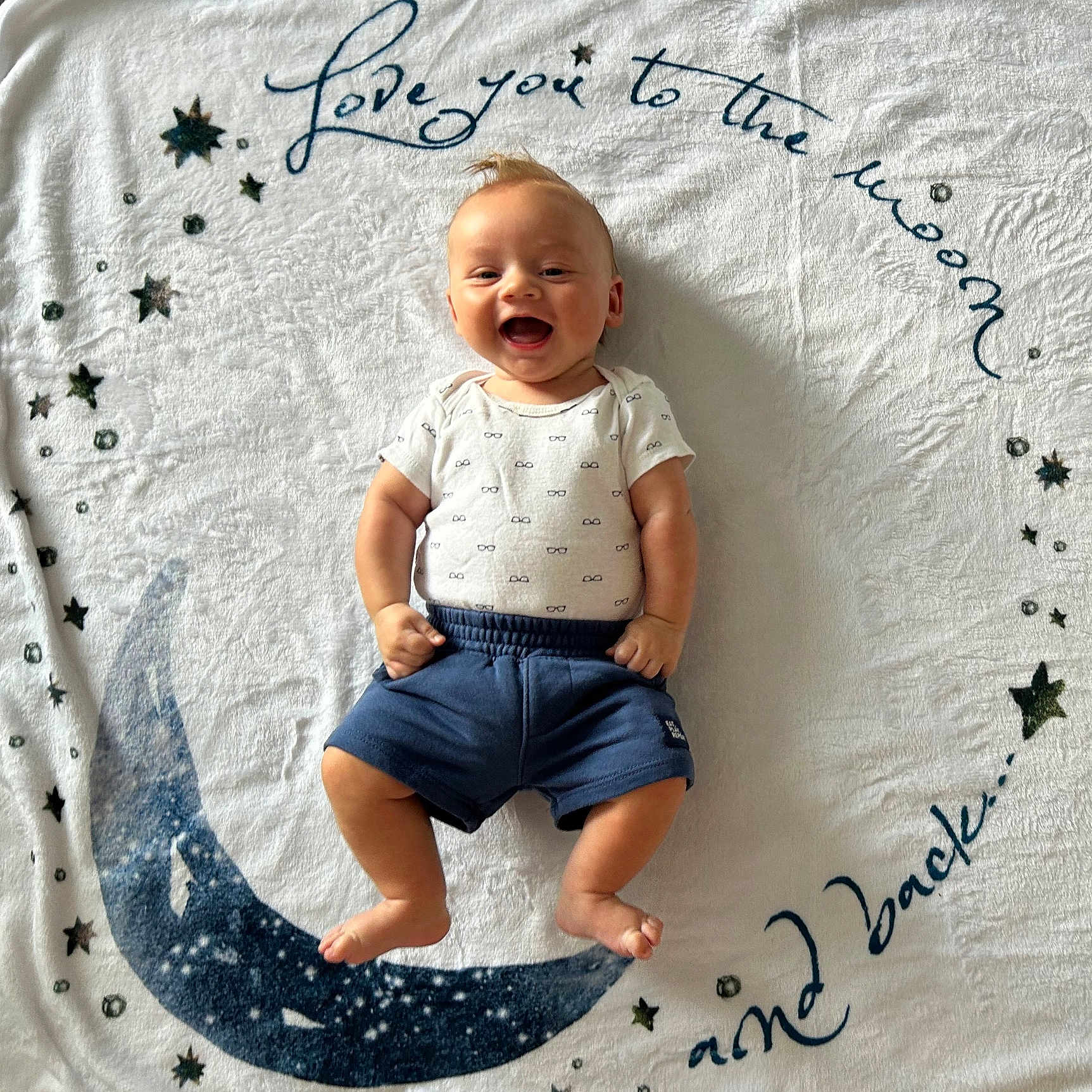 Carson joined the competition — help win amazing prizes! baby, baby_boy, blanket, child, clothing, cute, fabric, face, happy, indoor, infant, lying_down, moon, onesie, pattern, portrait, shorts, smiling, stars, text