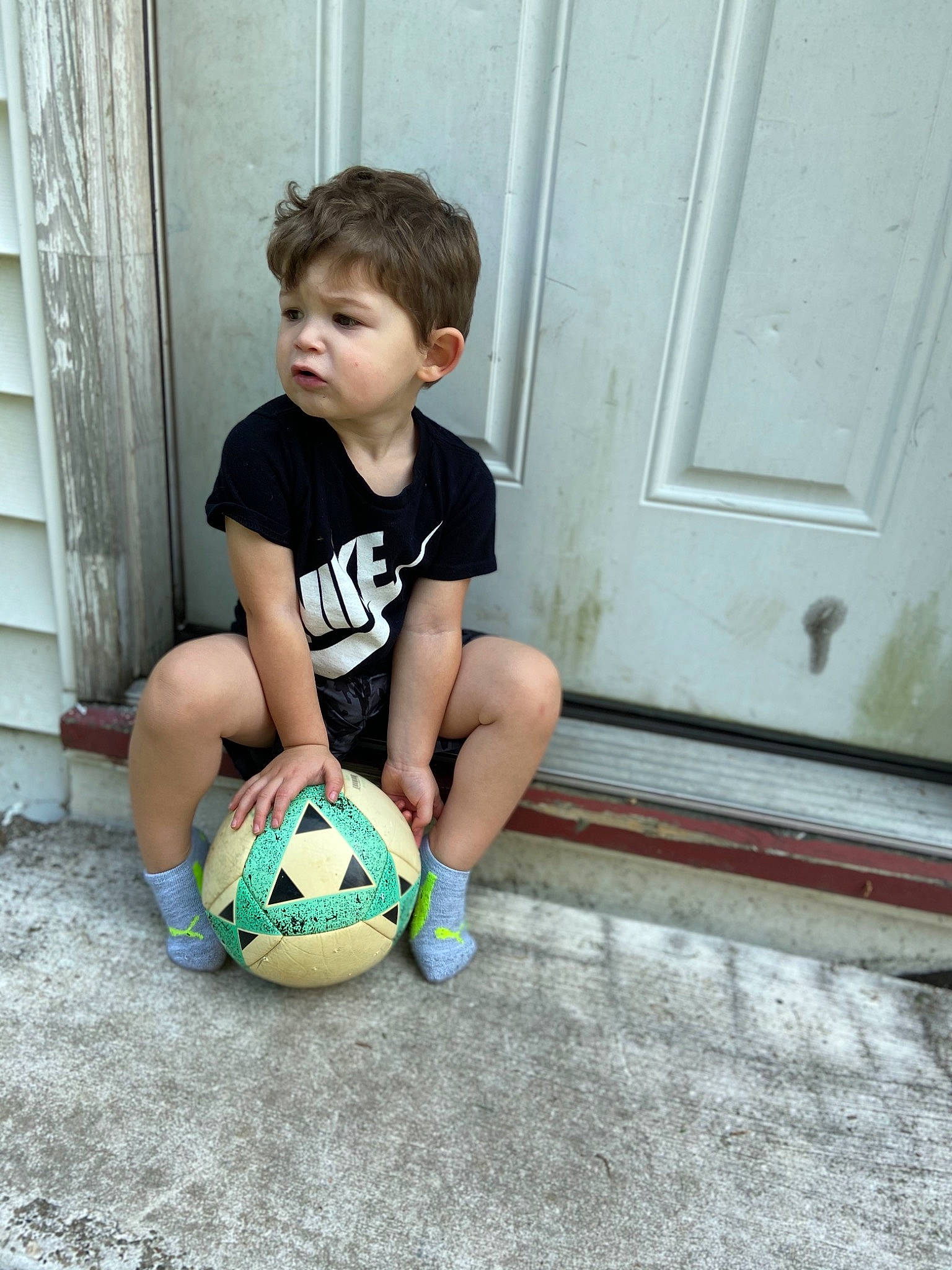 Caleb is registered to the contest to win money with this photo: ball, child, curtain, floor, flooring, football, fun, happy, hardwood, knee, leisure, person, shoe, shorts, sneakers, soccer, soccer_ball, sports_equipment, t_shirt, toddler