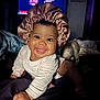 Isabella is registered to the contest to win money with this photo: baby, blanket, bonnet, child, clothing, crawling, cute, expression, eyes, face, happy, headwear, indoors, infant, person, portrait, satin, smile, toy, warm_lighting