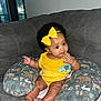 baby, bow, child, couch, curly_hair, cute, finger, hand, headband, indoor, infant, nursing_pillow, pacifier_clip, polka_dot, portrait, seated, skin, sofa, yellow_clothing, young_child