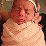 baby, newborn, swaddle, headband, bow, sleeping, closeup, infant, cozy, pink, hand_holding, blanket, face, eyes_closed, peaceful, skin, hair, nursery, portrait, fabric