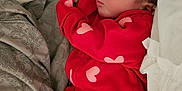 Kyliee is registered to the contest to win money with this photo: baby, newborn, sleeping, red_clothing, hearts_pattern, onesie, blanket, pillow, bedding, infant, cozy, portrait, bed, peaceful, closeup, soft_texture, cute, cuddly, indoors, resting