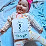 baby, infant, smiling, pink_bow, headband, blanket, pajamas, rainbow, sign, eight_months_old, lying_down, cute, happy, child, face, clothing, indoor, person, pattern, soft