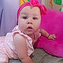 Stevie is registered to the contest to win money with this photo: baby, child, pink_headband, pink_clothing, crawling, cushion, bed, indoor, colorful_background, soft_texture, person, infant, portrait, cute, expression, headwear, comfort, playful, young, skin