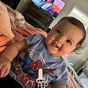 Ivy Jean joined the competition — help win amazing prizes! baby, child, toddler, spiderman, tshirt, smiling, drool, bed, blanket, indoor, television, furniture, person, face, curly_hair, cozy, relaxed, home, casual, happy