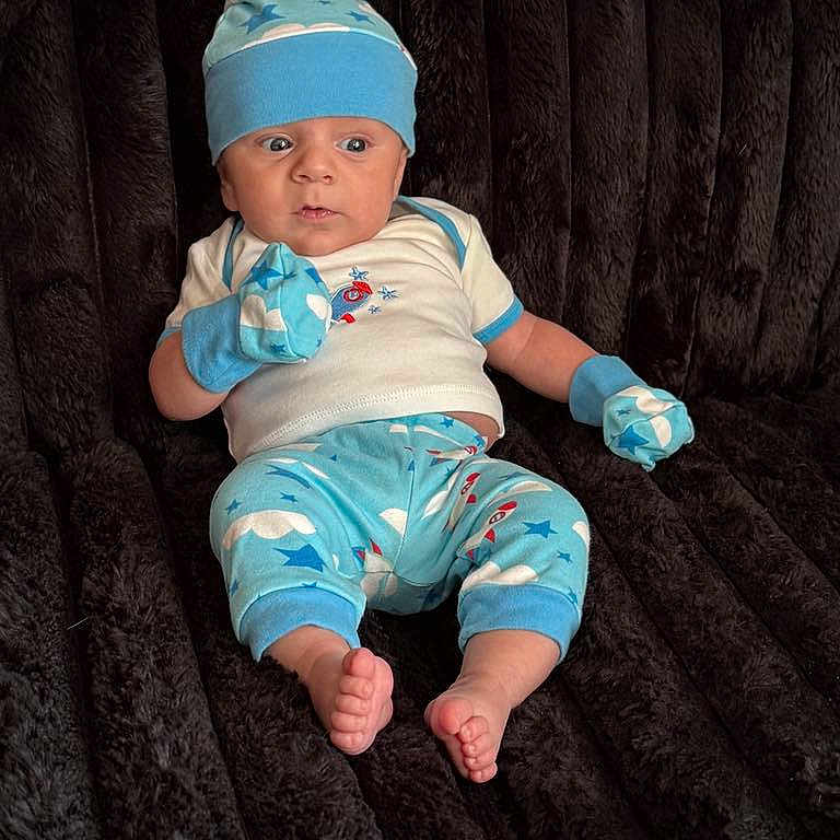 Michael is registered to the contest to win money with this photo: baby, bodypart, bonnet, cap, clothing, face, finger, glove, hand, hat, head, jeans, newborn, pajamas, pants, person, photography, portrait, shorts, sitting